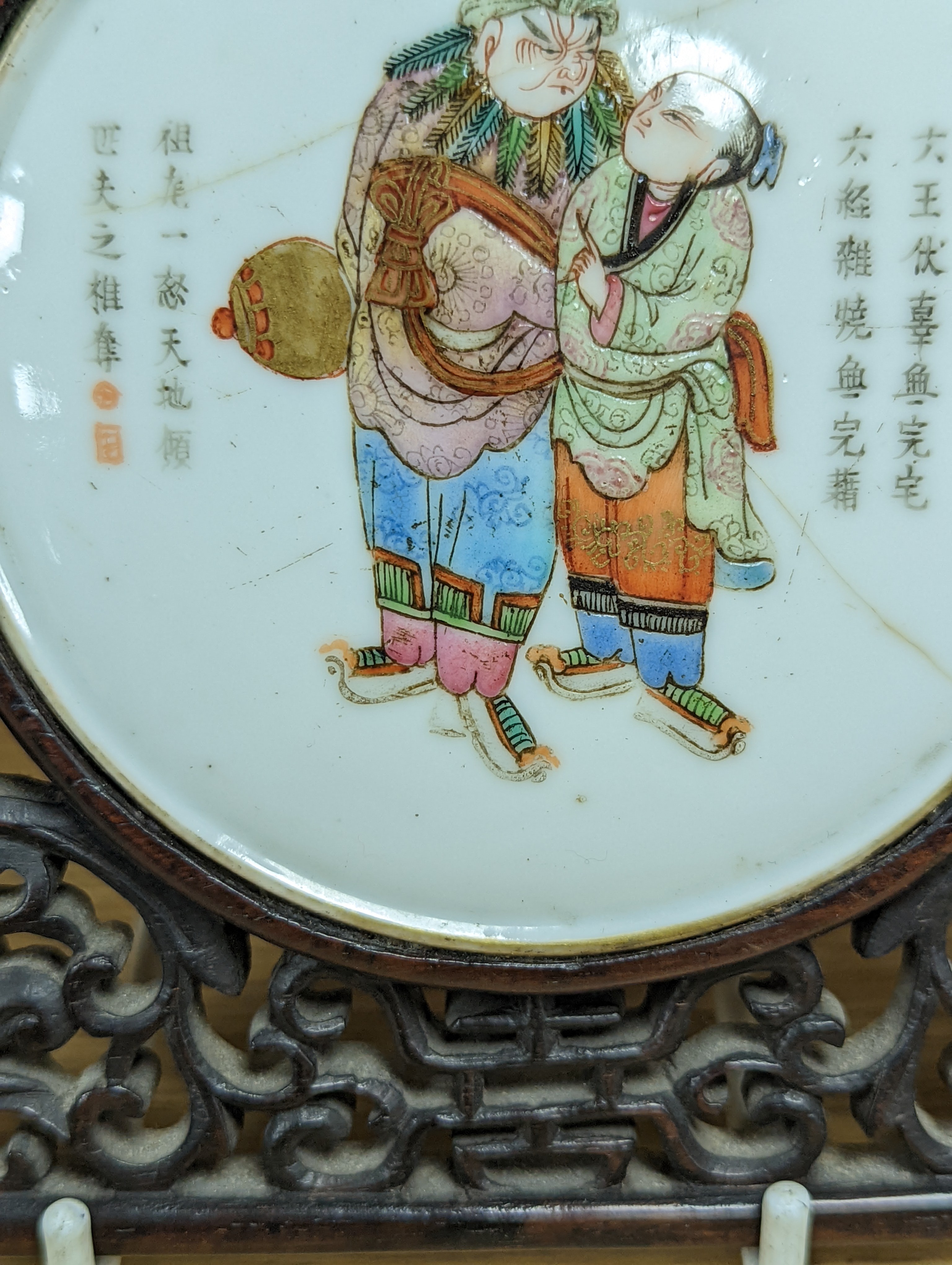 A 19th century Chinese famille rose circular plaque or cover, inset into a wood surround, cracks 15cm sq